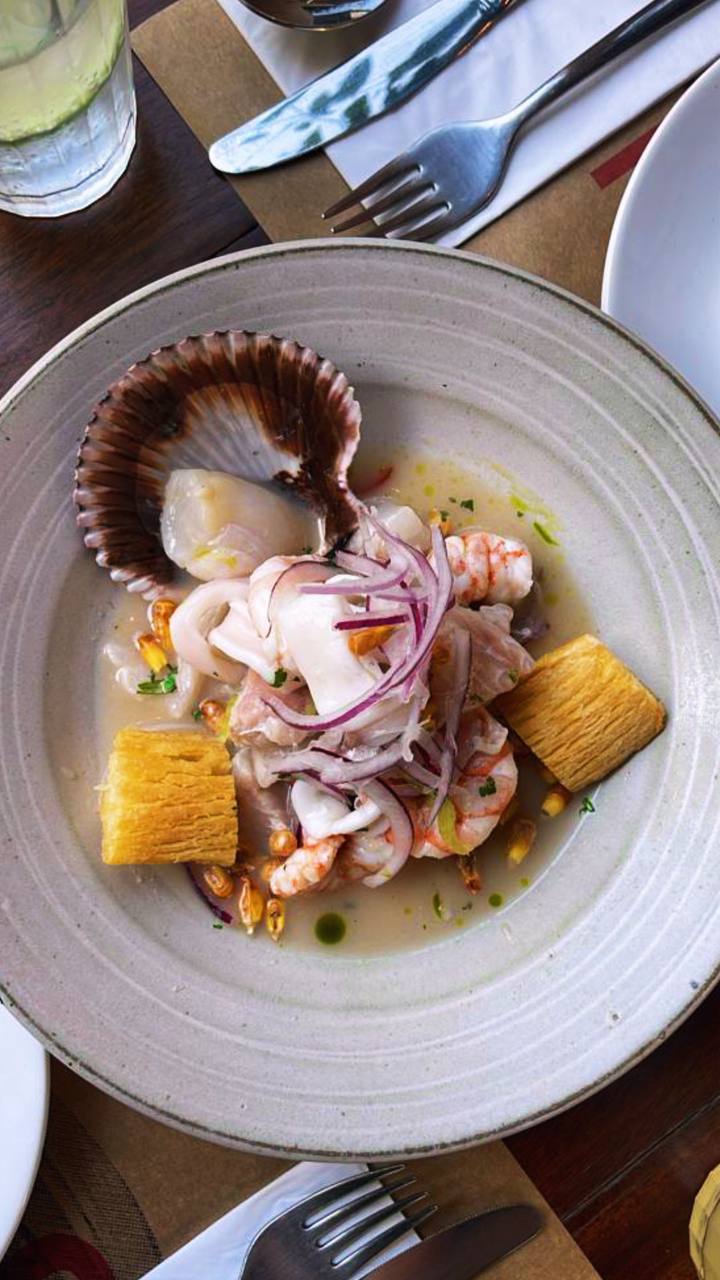 Prato elegante com polvo, camarão, batata e molho em prato branco